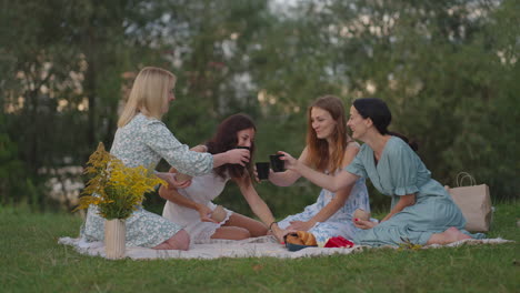 young women after modeling from clay discuss the resulting products drink tea coffee drinks laugh communicate in nature in the open air. creative activity hobbies picnic.