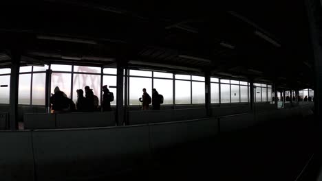 Silhouette-view-of-travelers-walking-in-the-outside-airport-terminal-after-flight-landing---Brussels-international-airport,-Belgium