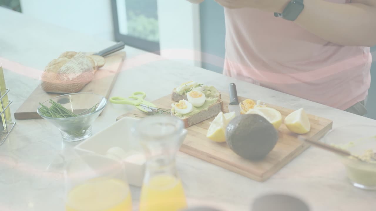 Woman preparing breakfast on countertop, hands reaching for eggs and avocado, slicing toast