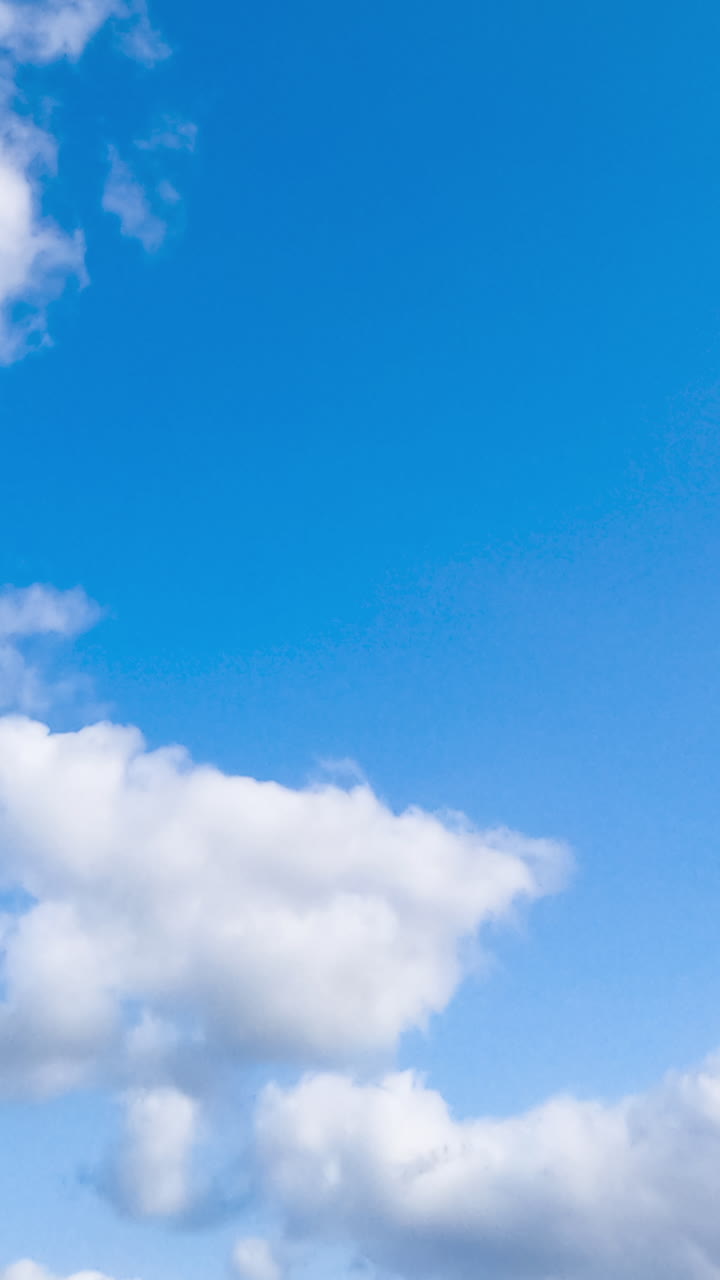 Blue clear sky with soft fluffy clouds. Beautiful azure summer sky with clouds quickly changing shapes. Timelapse. Vertical video