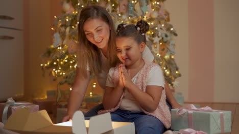 niña y mujer abren caja de regalo, sale luz dorada, se sorprenden