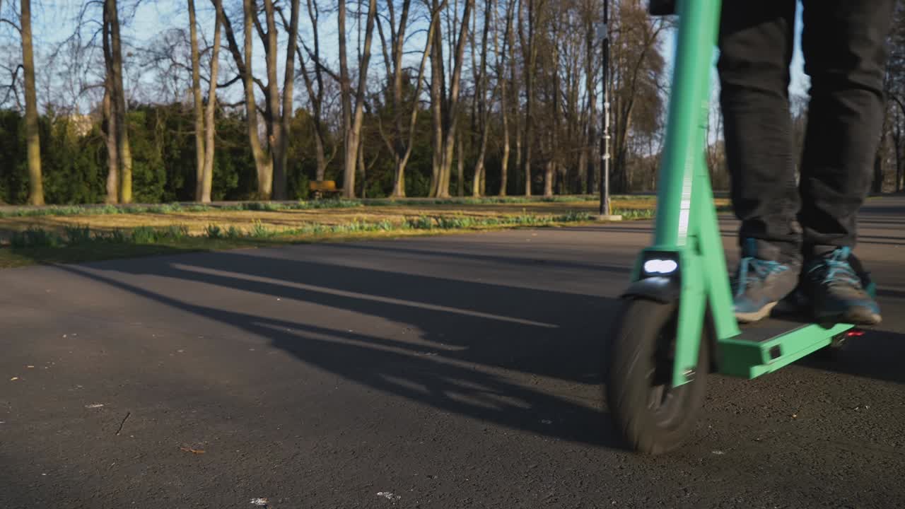 전기 스쿠터를 탄 남자가 카메라 앞에서 오른쪽에서 왼쪽으로 지나간다