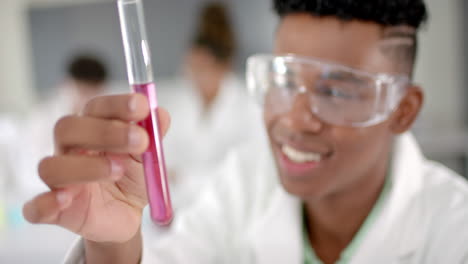 teenage biracial boy examines a test tube in a high school laboratory