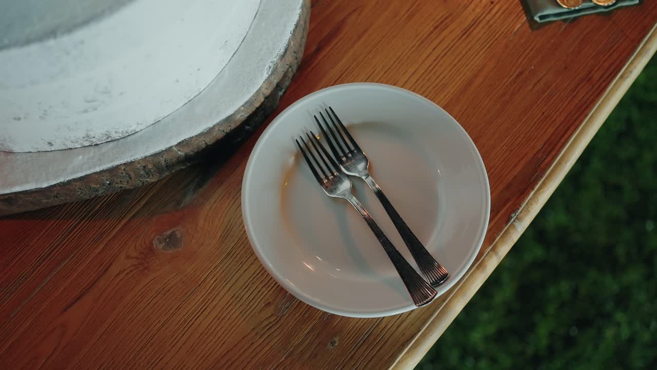 Close up of two forks on a plate beside wooden cake stand location irrelevant