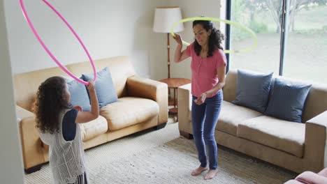 Mixed-race-mother-and-daughter-playing-with-hula-hoops