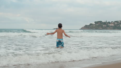 joyful boy playing in sea surf. happy teenager enjoying time at beach.