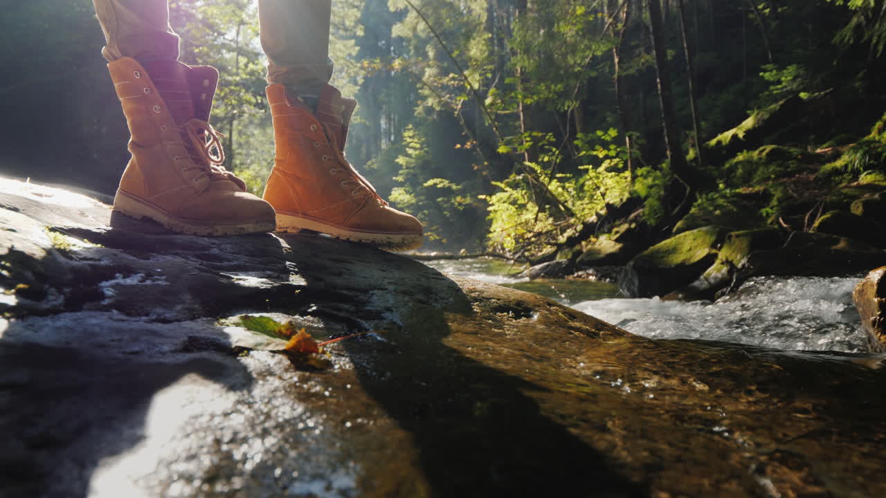 여행자의 발은 계류 관광 및 하이킹 개념 근처의 젖은 통나무에 서 있습니다.