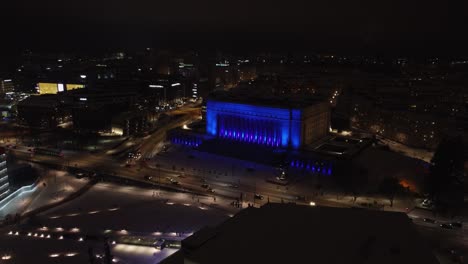 Aerial:-Night-traffic-drives-past-Helsinki-Parliament-House-in-blue