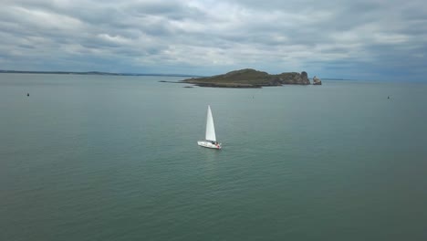 Beautiful-Pan-right-to-left-of-sail-boat-in-front-of-an-island,-shot-in-4K