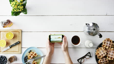 top view man browsing vacation photographs using smartphone at breakfast belgian waffles and coffee hands from above - red epic dragon