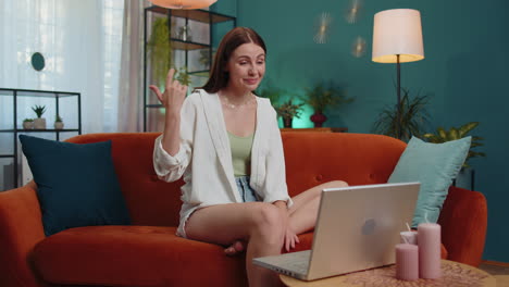 woman sitting on home couch, looking at camera, making video conference call with friends or family