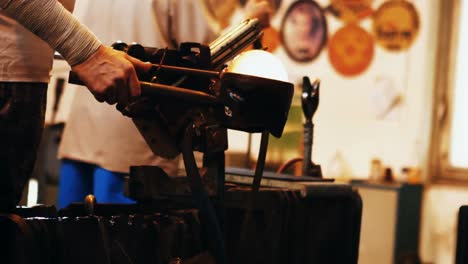 mid section of glassblower shaping a molten glass