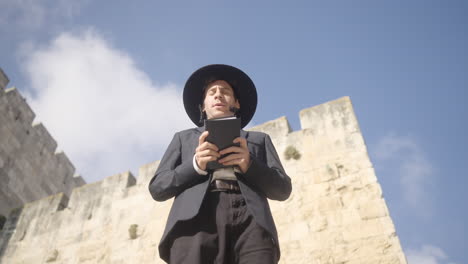 orthodox jewish man praying holding torah hebrew bible in jerusalem, israel