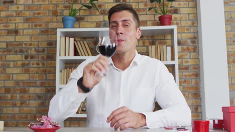 hombre caucásico haciendo una videollamada bebiendo un vaso de vino tinto y hablando