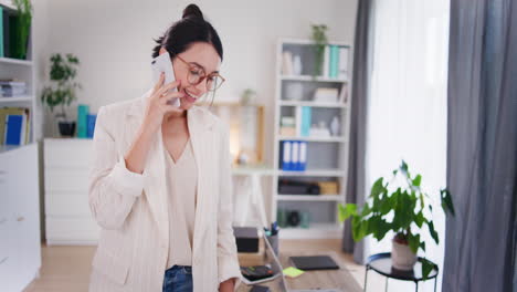 Glückliche-Frau-Telefoniert-Im-Büro-Mit-Handy