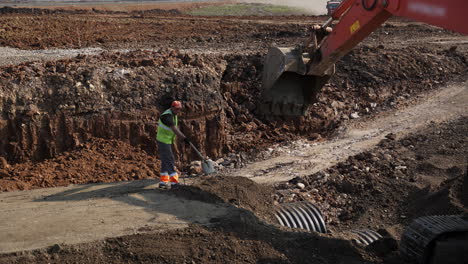 construction worker and excavator at a dirt excavation site