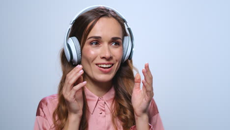 Businesswoman-listening-music-in-headphones-at-studio.-Worker-clapping-in-hands