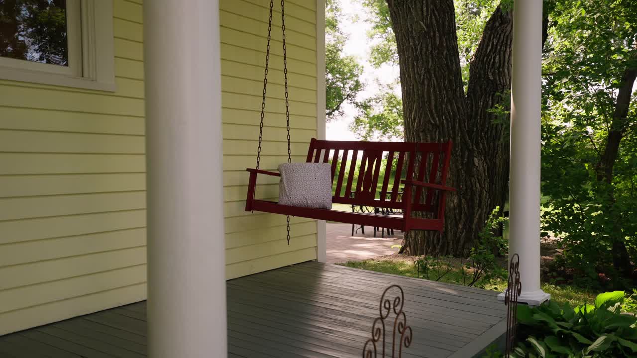 disparo en órbita de un columpio rojo colgado en la cubierta delantera de una granja