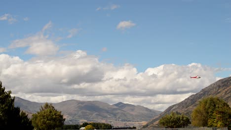 helicopter crossing static frame with clouds and mountains in background