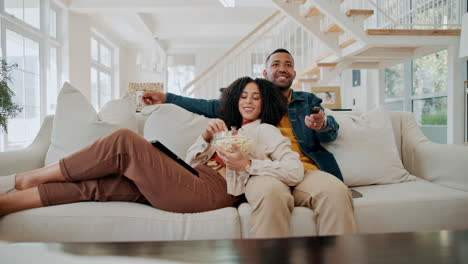 couple relaxing on couch watching tv with popcorn