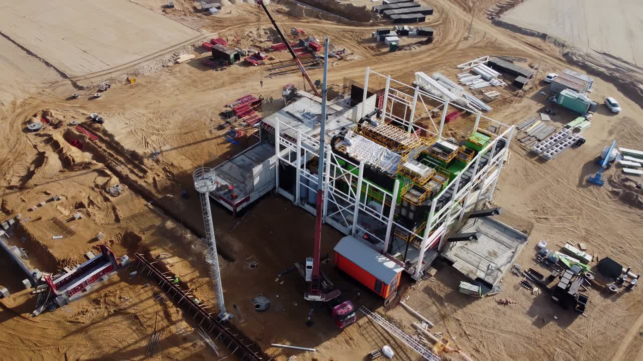 vuelo aéreo sobre un nuevo sitio de desarrollo de construcciones proyectos de almacenes y maquinaria pesada y trabajadores de la construcción están trabajando en la zona.