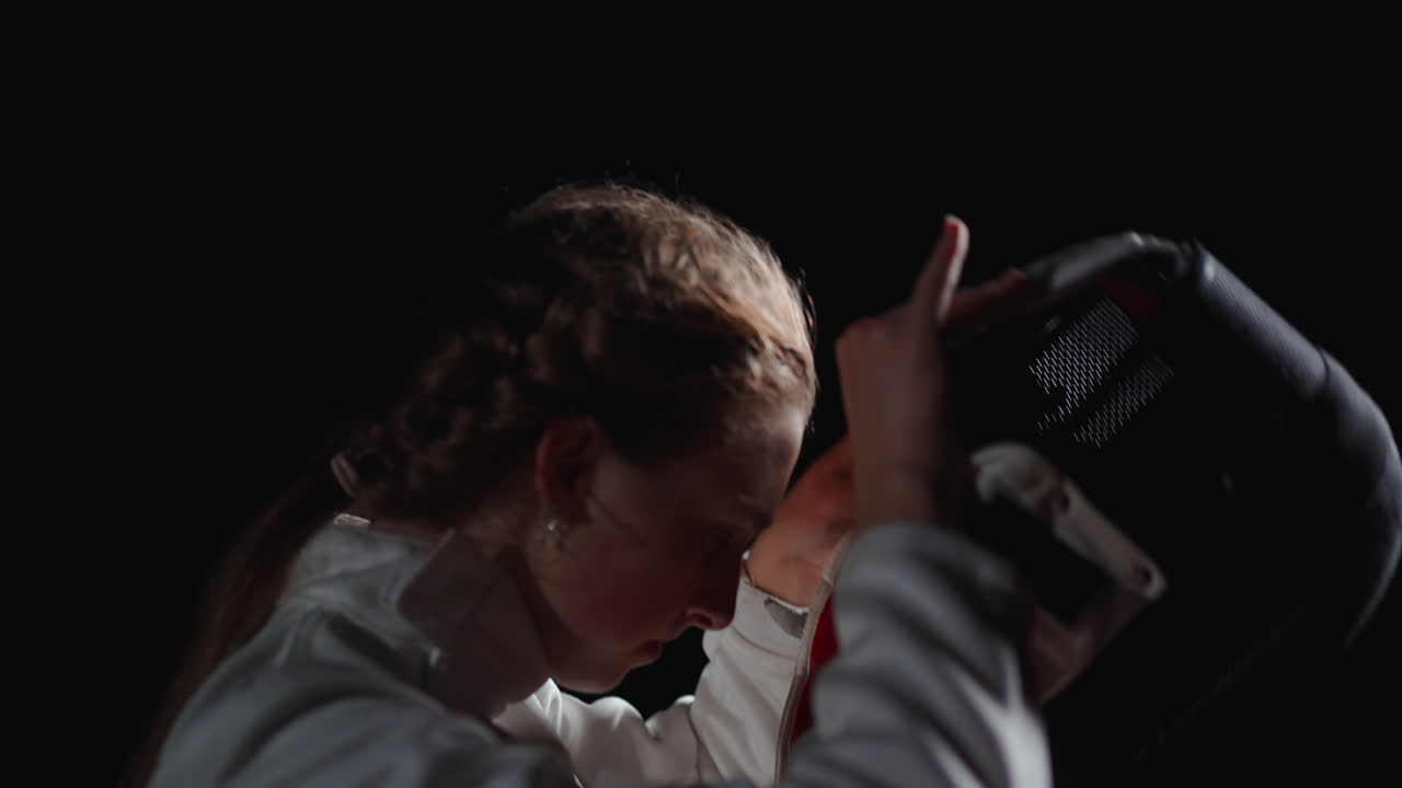 보호 장비와 마스크를 착용한 젊은 여성 펜싱 선수