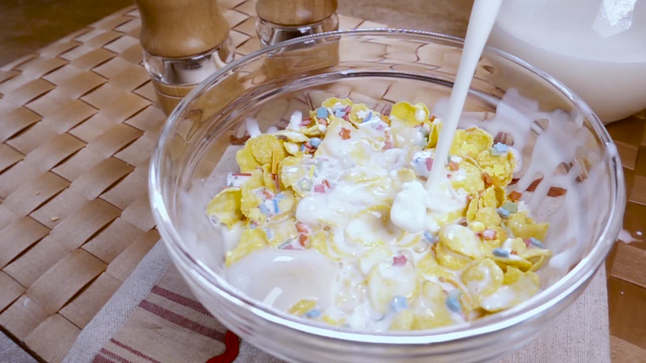Fiocchi di mais gialli croccanti nella ciotola per una deliziosa colazione mattutina con latte. Slow motion con ripresa rotatoria.