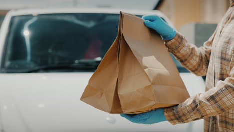 A-Delivery-Officer-Hands-Food-Packages-To-The-Recipient