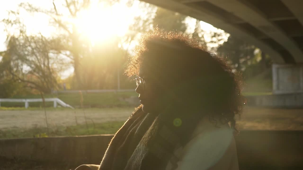 Curly black woman portrait standing in front of the winter sun