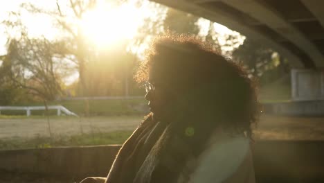 curly black woman portrait standing in front of the winter sun