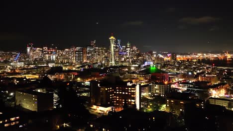 city of seattle skyline at night from a distance, aerial over lit neighborhood in the dark