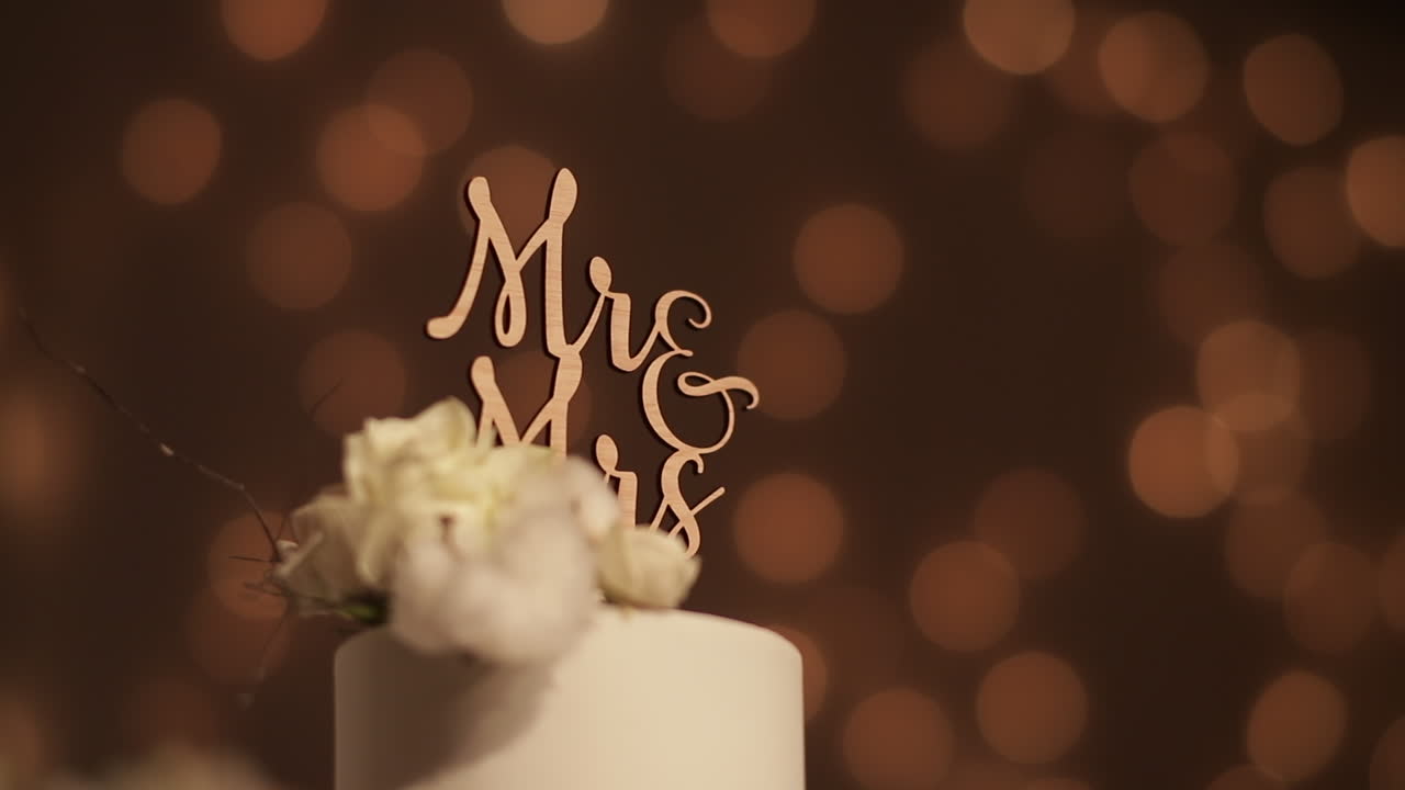 Cake topper "Mr e Mrs" su torta bianca, sfondo bokeh.
