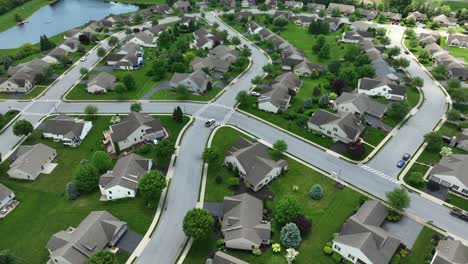 car on street of new developed housing area with luxury single family houses and lake. american suburb district in town of pennsylvania. well manicured lawn of garden grass in spring. aerial view.