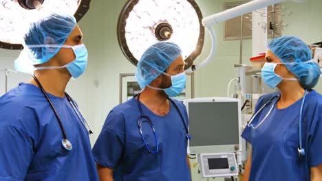 cirujanos masculinos y femeninos interactuando entre sí en la sala de operaciones
