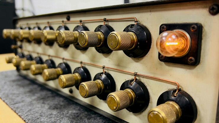 Panning camera across vintage panel on bench, showing knurled terminals, copper wires, glowing lamp