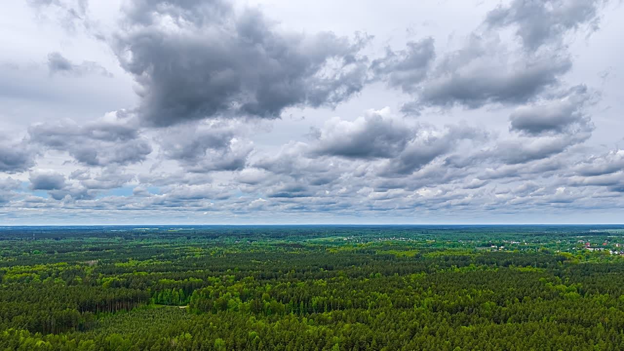 Expansive green landscape viewed from above with dramatic cloud-filled sky