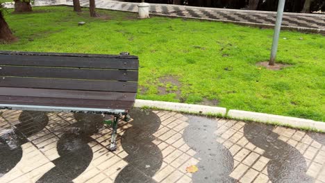 panning view of empty bench in a park in the rain. daylight