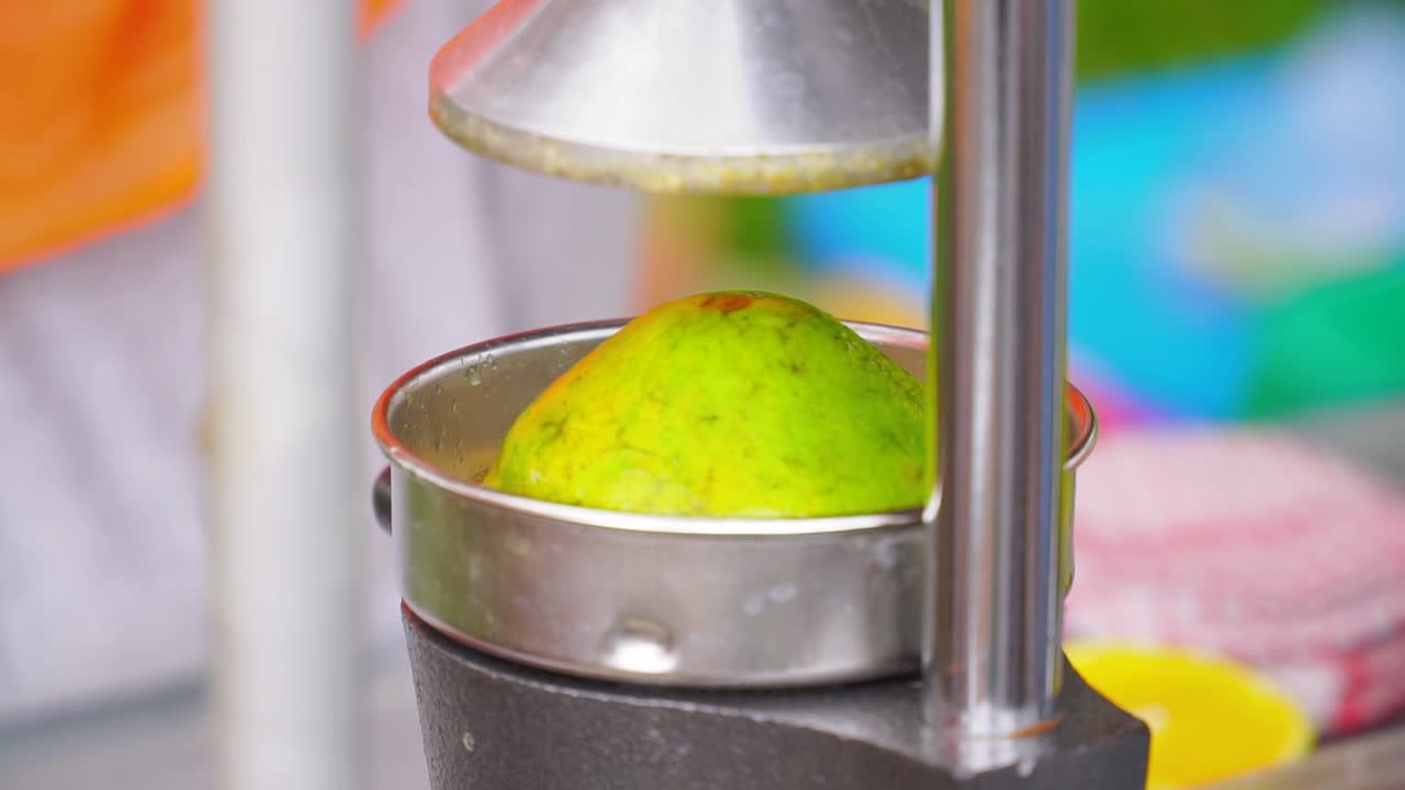persona que opera la máquina exprimidora de cítricos haciendo jugo de naranja fresco, de cerca