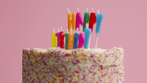 foto de estudio de pastel de cumpleaños giratorio cubierto con decoraciones y velas que deletrean feliz cumpleaños 5