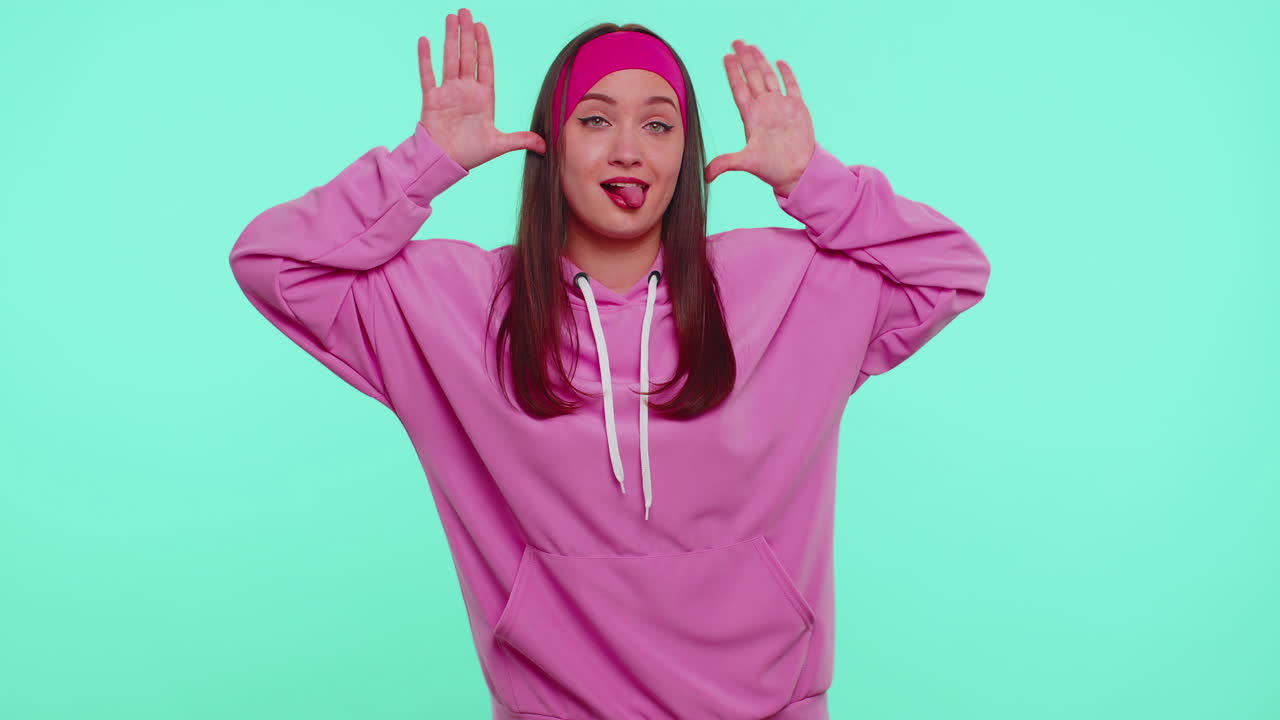 재미있는 십대 소녀는 장난스러운 어리석은 얼굴 표정을 하고 미소 짓고, 혀를 보여주며 어리석습니다.