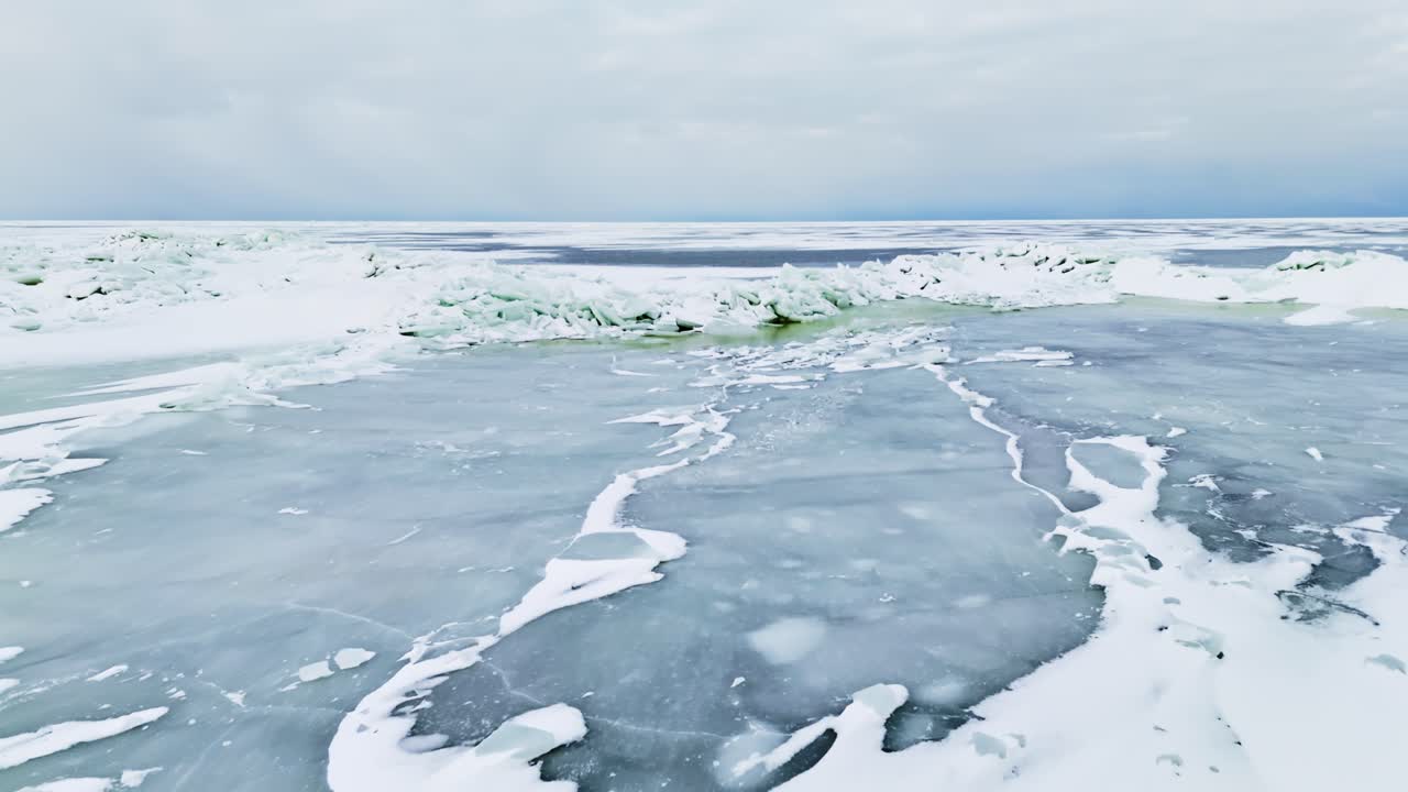 Вид с дрона на торос морского льда с зеленым каналом талой воды на переднем плане под облачным небом. Суровый зимний морской пейзаж, показывающий риск оттепели и концепцию изменения климата