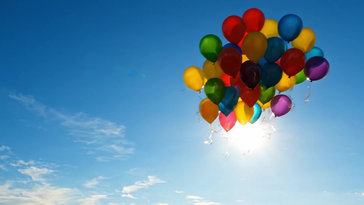 Una vivace collezione di palloncini colorati si libra nel cielo azzurro e limpido, illuminata da un sole splendente, catturando la gioia e la libertà del momento
