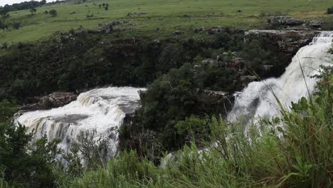 toma estática de hierba meciéndose con el viento en primer plano, con las cataratas de lisboa en el fondo