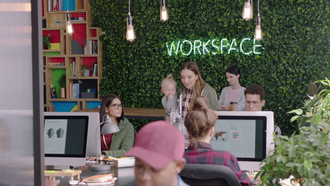 mujer de negocios feliz madre sosteniendo al bebé gerente de oficina comprobando a los colegas compartiendo ideas discutiendo el trabajo en un lugar de trabajo de oficina moderno diverso
