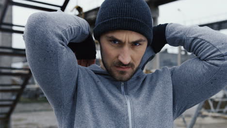 caucaisan male boxer wearing a grey hood and starting to kick angry to the camera