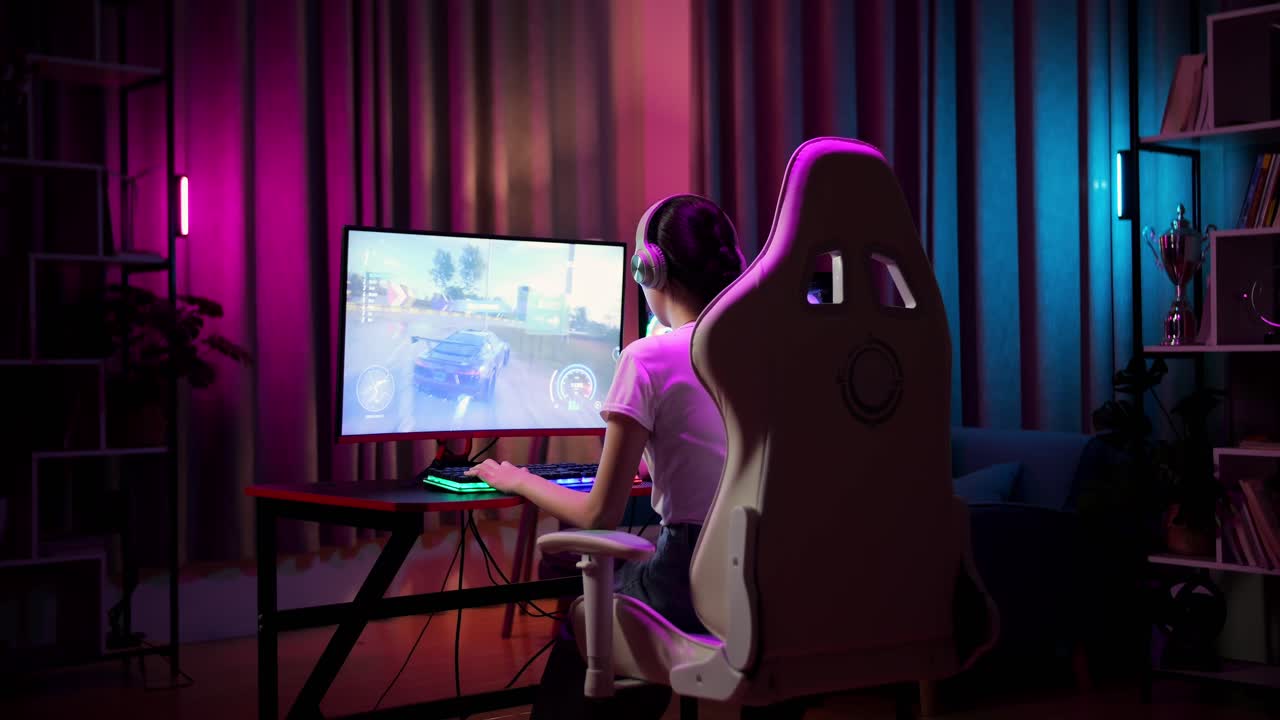 Adolescente asiatica gamer con le cuffie che gioca a un videogioco di corse al computer.