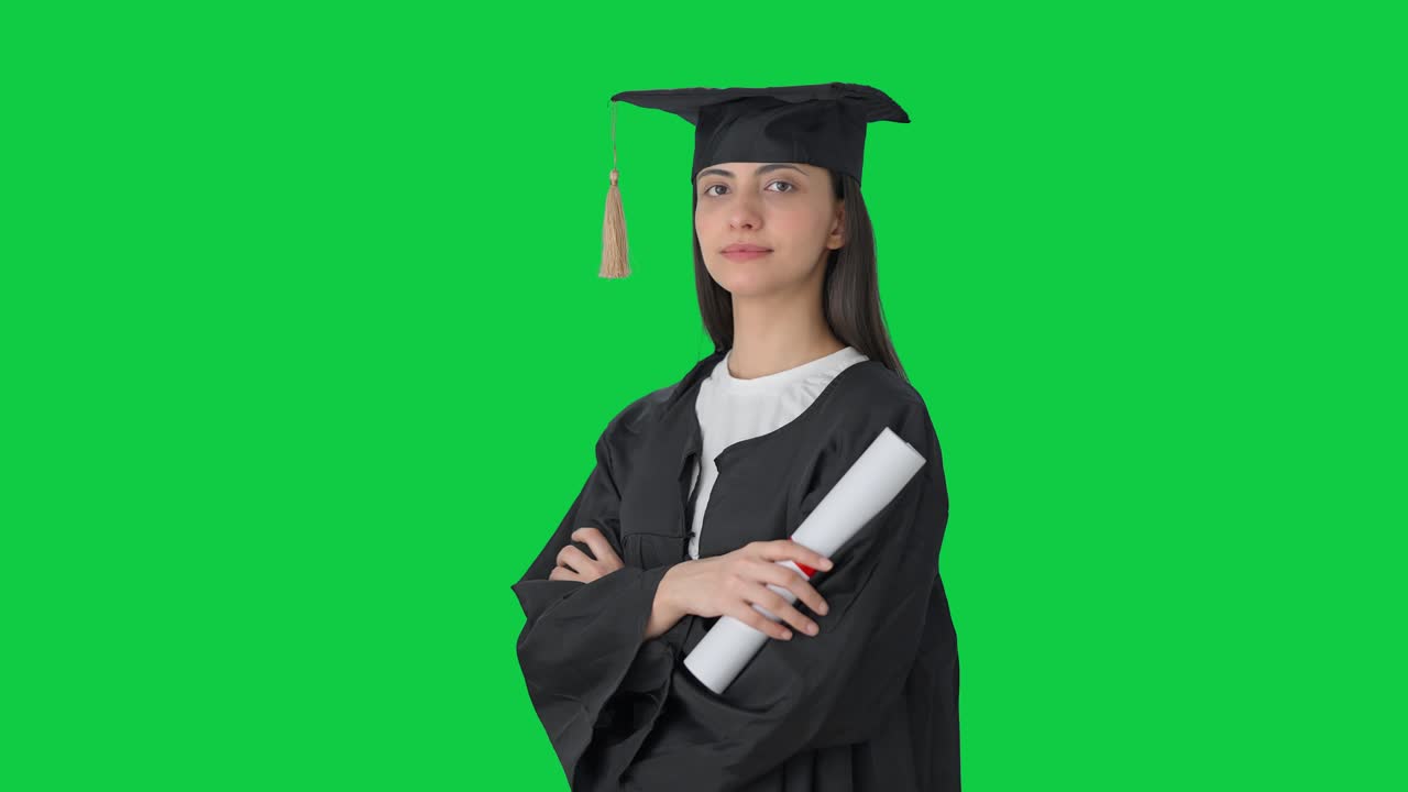 Ritratto di una ragazza indiana laureata in piedi a braccia incrociate. Schermo verde.