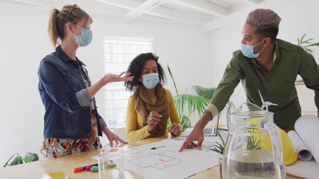 compañeros de oficina con máscaras en la cara discutiendo sobre documentos en la oficina