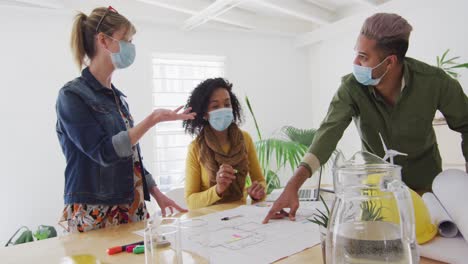 Office colleagues wearing face mask discussing over documents at office