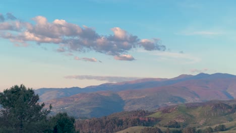 white clouds drifting over a mountain landscape in a blue sky. time lapse shot.
